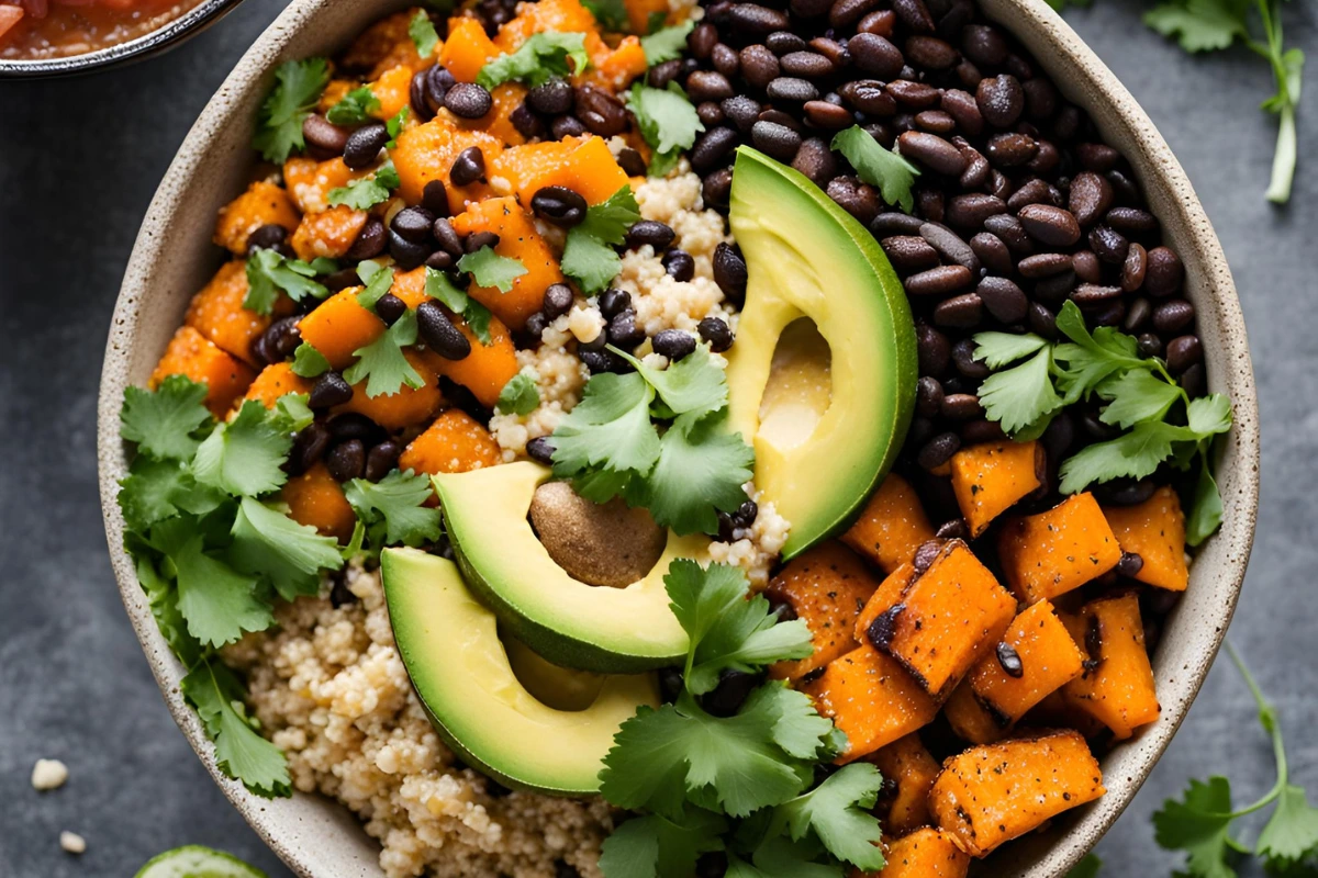 Overhead view of a colorful burrito bowl with quinoa, black beans, roasted sweet potatoes, and toppings like avocado and salsa.